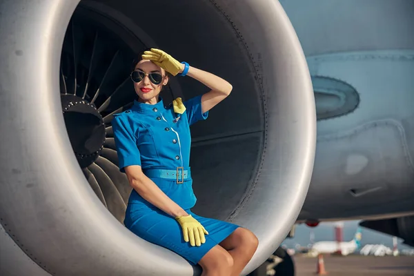 Улыбающаяся красивая стюардесса сидит рядом с пассажирским самолетом — стоковое фото