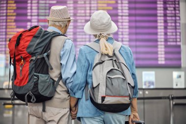 Uçuş bilgi ekranına bakan iki yaşlı turist