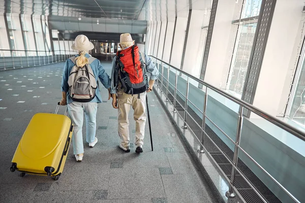 공항 터미널을 따라 가는 연로 한 관광객 부부 — 스톡 사진