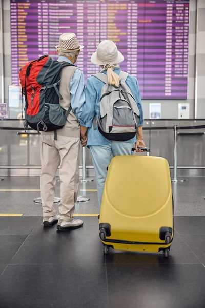 Casal de turistas em pé em frente ao tabuleiro de partidas — Fotografia de Stock