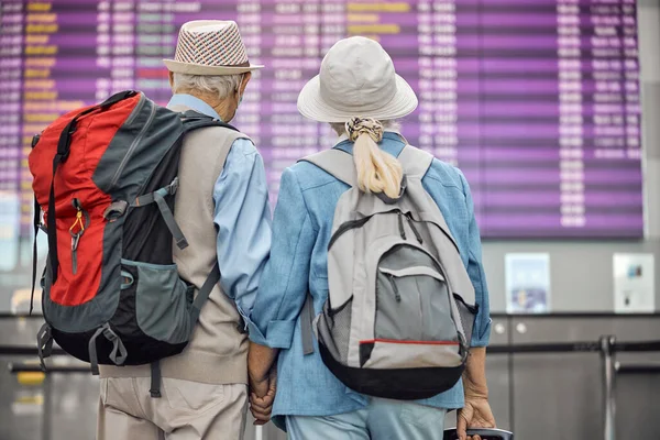 Uçuş bilgi ekranına bakan iki yaşlı turist — Stok fotoğraf