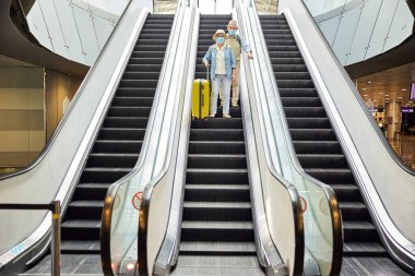 Yürüyen merdivenden inen iki yolcu.