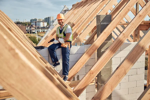 Construtor sorridente em um chapéu duro segurando um motorista de broca — Fotografia de Stock