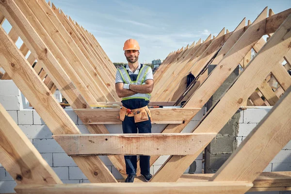 Vrolijke man in een harde hoed poseren in de buurt van bouwplaats — Stockfoto