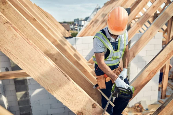 Constructor profesional en un sombrero de trabajo duro con una motosierra — Foto de Stock