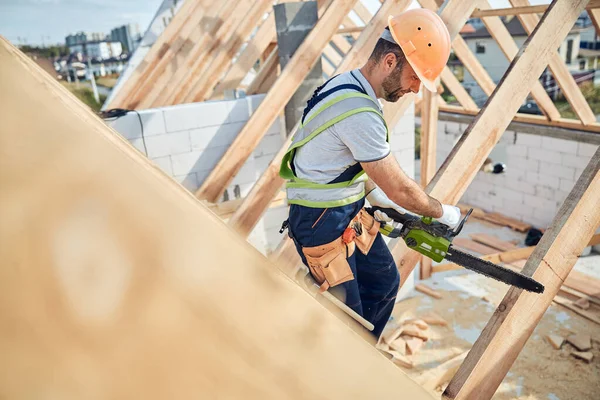 Construtor certificado usando uma motosserra em um local de construção — Fotografia de Stock