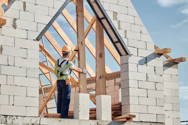 Homem concentrado em equipamentos de segurança construindo uma casa — Fotografia de Stock
