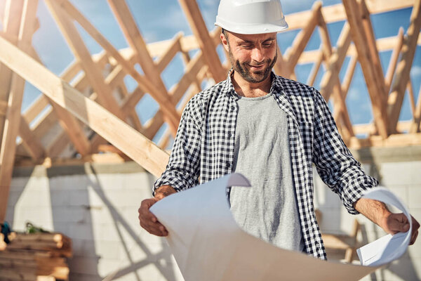 Gladsome engineer looking at a building plan on paper