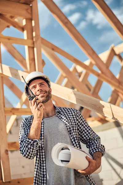 Vidám fiatalember walkie-talkie-t használ egy építkezésen. — Stock Fotó