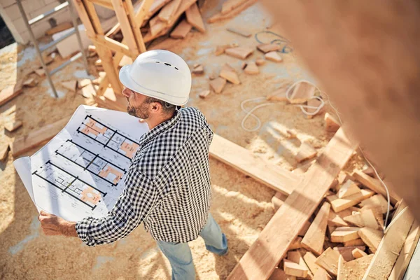 Construtor comprometido verificando plantas de uma casa — Fotografia de Stock