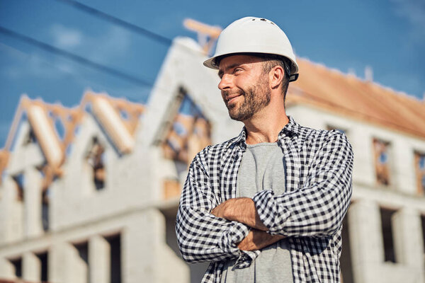 Cheerful architect posing proudly in front of his project building