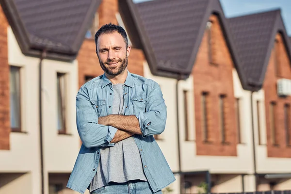 Lykkelig skjeggete mann som poserer nær et nytt hus – stockfoto