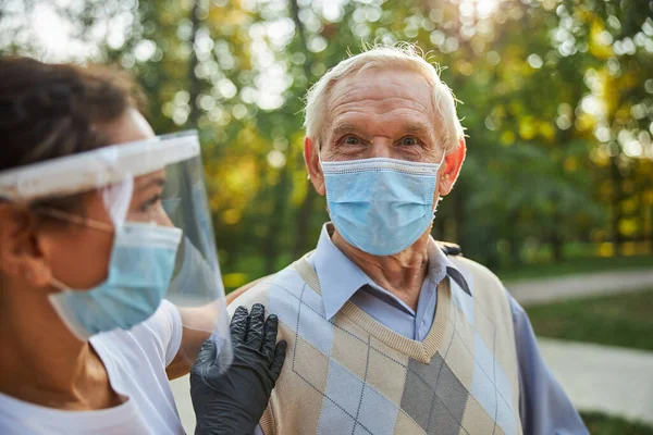 Knappe oudere man in casual kleding lachen in de buurt van de maatschappelijk werker — Stockfoto