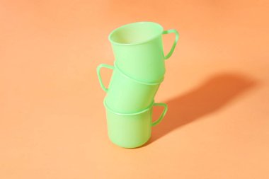 Turuncu bir arka plan üç açık yeşil plastik bardağa sahiptir                