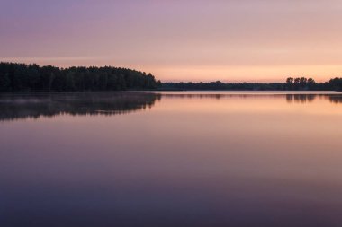 Orman gölünün üzerinde gün doğumu. Göldeki gökyüzünün yansıması. Yaz.