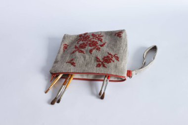 Keten kumaştan yapılmış ve kırmızı ipliklerle işlenmiş makyaj çantası. Kişisel bileklik çantası. Hafif arkaplan.