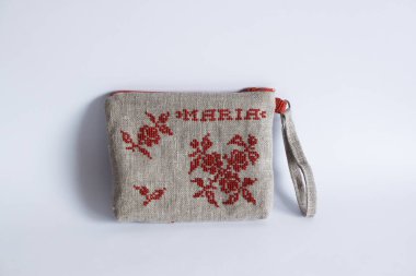 Keten kumaştan yapılmış ve kırmızı ipliklerle işlenmiş makyaj çantası. Kişisel bileklik çantası. Hafif arkaplan.