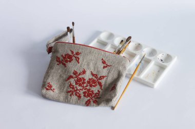 Keten kumaştan yapılmış ve kırmızı ipliklerle işlenmiş makyaj çantası. Kişisel bileklik çantası. Hafif arkaplan.