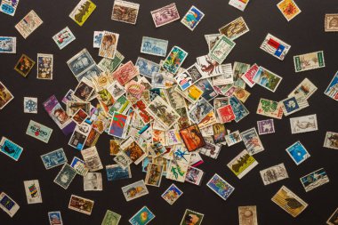 Various old postage stamps scattered on a dark background. clipart