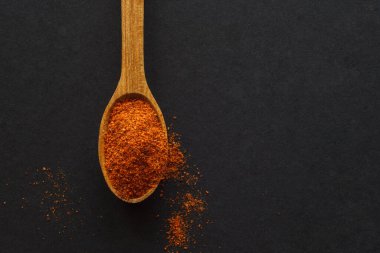 Koyu arka planda acı biberli ahşap bir kaşık. Yukarıdan bak. Metin için boşluk olan koyu arkaplan.