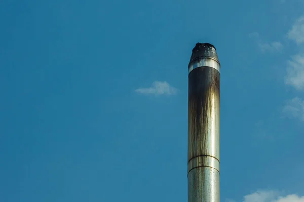 Metal smoke pipe on blue sky background. Copy space.