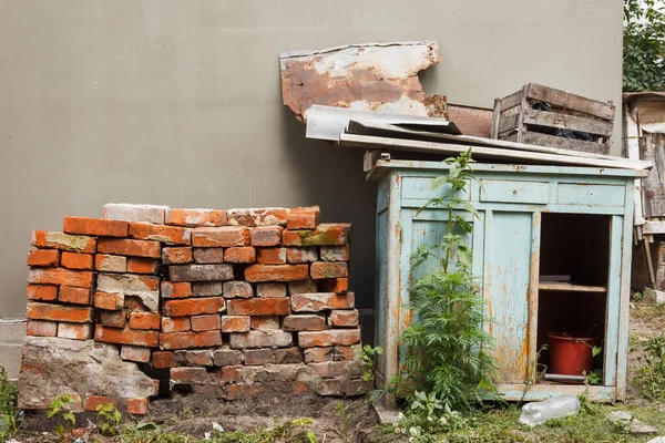 Folded old red brick and broken kitchen cabinet in the backyard. Backyard with building rubbish. Rural courtyard.