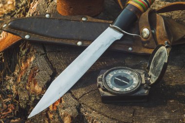 Avcı bıçağı, deri kılıf, kemer ve dışarıdaki eski ordu pusulası. Av ekipmanlarıyla hayat devam ediyor. Yakın plan..