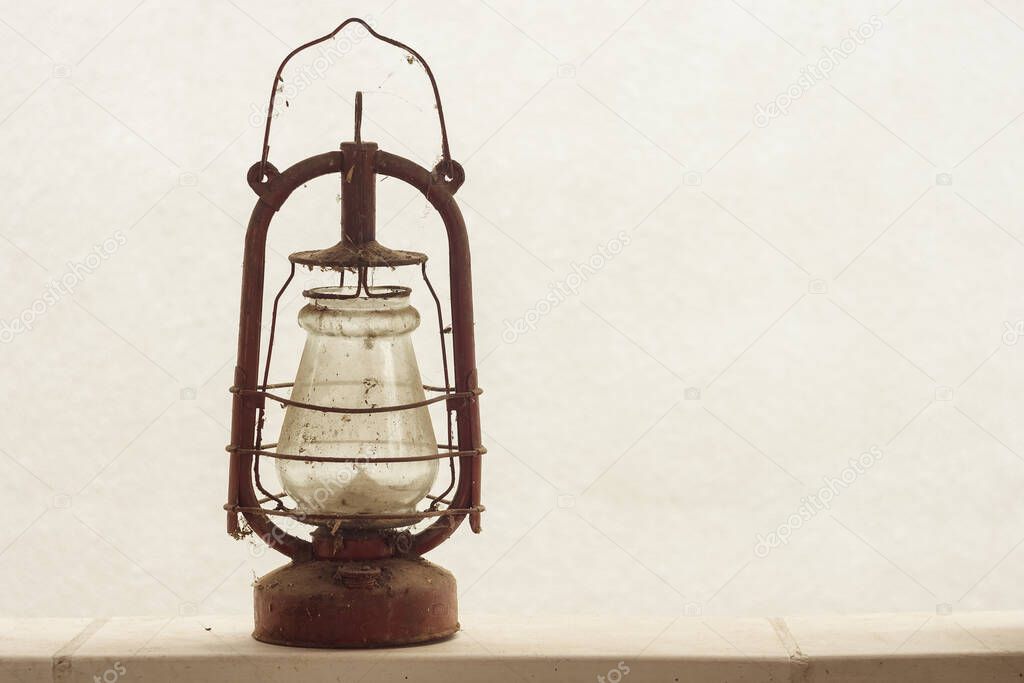 An old vintage kerosene lamp on the background of a white wall. Copy space.