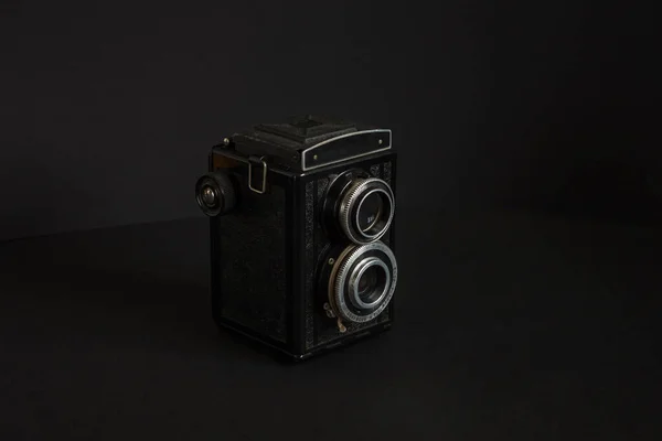 Old analog camera with two lenses on a black background. Copy space.