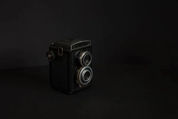 Old analog camera with two lenses on a black background. Copy space.