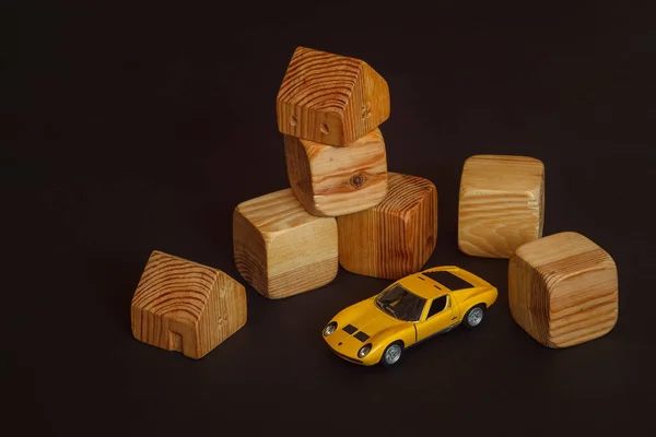 Wooden building blocks for kids. Toy building made of wooden cubes. Toy car model among wooden cubes