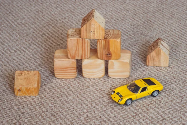 Wooden building blocks for kids. Toy building made of wooden cubes. Toy car model among wooden cubes