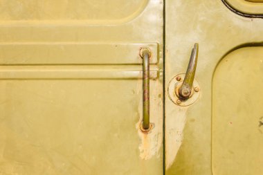 Askeri araç kapısı için kapı kolu. Eski Sovyet askeri teçhizatının tasarım unsurları ve detayları. Askeri yeşil kamuflaj metal arka planı. Yakın çekim.
