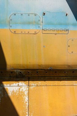 Eski bir uçağın gövdesinin detayları. Eski kamuflaj yüzeyi, pul pul dökülmüş boya ve askeri bir uçağın perçinlenmiş perçinleriyle..