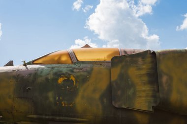 Gökyüzü arka planında eski bir jet uçağının gövdesi ve kokpiti. Parça. Eski bir kamuflaj yüzeyinin ayrıntıları. Askeri bir uçağın üzerinde deri dökülmüş boya var..