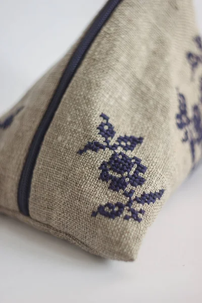 Linen cosmetic bag with a blue embroidery. Light background