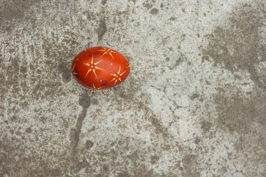 Gri bir beton yüzeyin arka planında kırmızı renkli Ukrayna paskalya yumurtası boyadı.