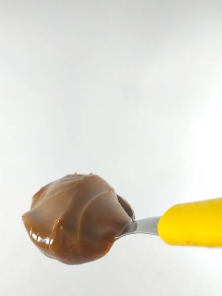 Sarı kaşıkta fıstık ezmesi.