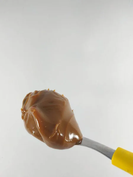 Sarı kaşıkta fıstık ezmesi.