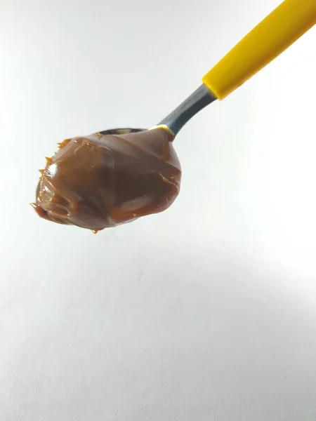 Sarı kaşıkta fıstık ezmesi.