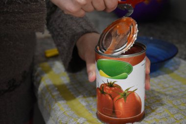 Kadın bir kutu domates açıyor.