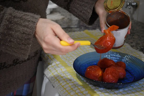 Kadın bir kutu domates açıyor.