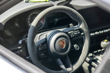 Brno, Çek Cumhuriyeti - 3 Eylül 2025: Porsche 911 yarış süper arabasının iç mekanı. Logo ve kontrol düğmeleri olan direksiyonun ayrıntıları.
