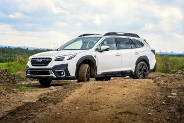 Prag, Çek Cumhuriyeti - 1 Kasım 2024: Beyaz Subaru Outback ailesi arazi aracı çamurlu bir off-road üzerinde sürüyor.