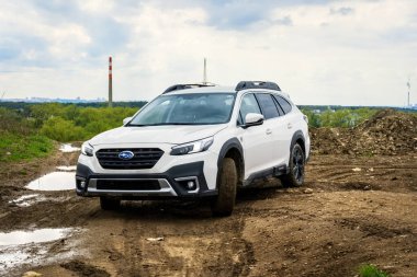 Prag, Çek Cumhuriyeti - 1 Kasım 2024: Beyaz Subaru Outback ailesi arazi aracı çamurlu bir off-road üzerinde sürüyor.