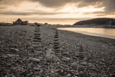 Kuzey Galler 'de kayalık bir sahilde çakıl taşlarını dengelemek. Llandudno çakıl taşı plajında akşam
