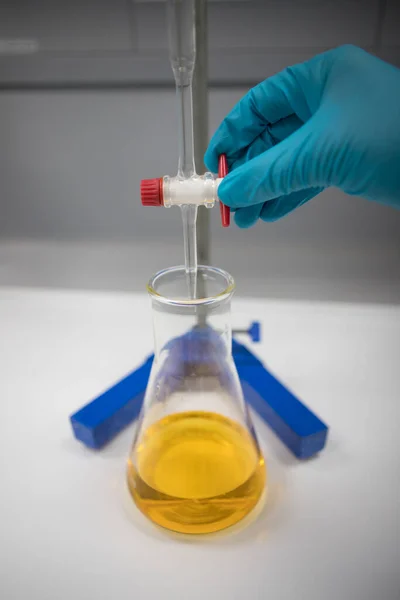 Titration of a solution using an orange indicator. Chemist in a pharmaceutical laboratory