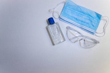 Koronavirüsün yayılmasını önlemek için koruyucu ekipman. Yüz maskesi, güvenlik gözlükleri ve alkol el jölesi.