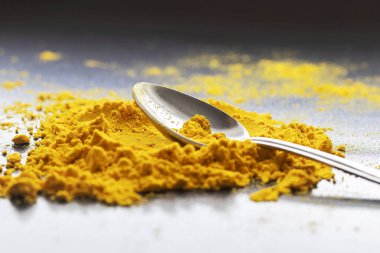 Gri masa arkaplanının üzerinde kaşık içinde baharat. Kopyalama alanı olan üst görünüm