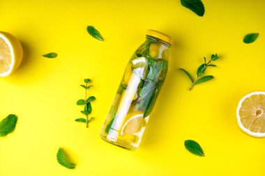 Detoks meyve suyu, narenciye ve nane yaprakları sarı arka plan üzerinde infüzyon. Düz yatıyordu yaz yaz içeceği ile arka plan. Üstten görünüm. Kopya alanı